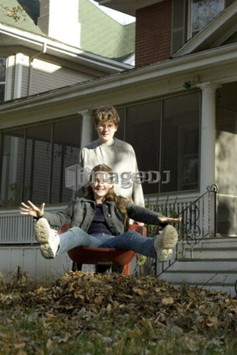 Teen brother carrying sister in wheelbarrow, Winnipeg, Canada