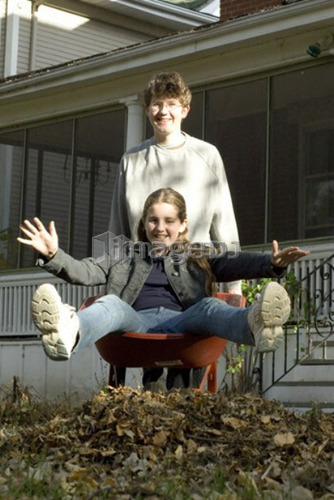 Teen brother carrying sister in wheelbarrow, Winnipeg, Canada