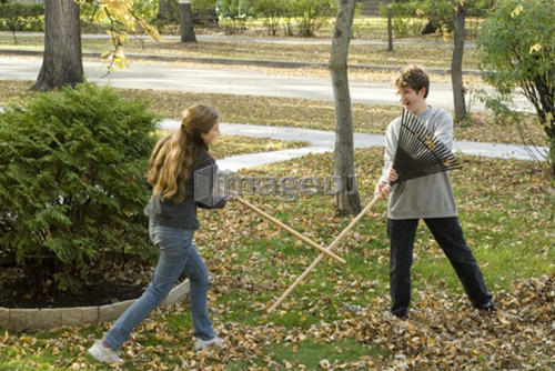 Teen brother and sister fighting with rakes, Winnipeg, Canada