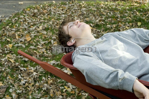 Teen boy listening to music in wheelbarrow, Winnipeg, Canada