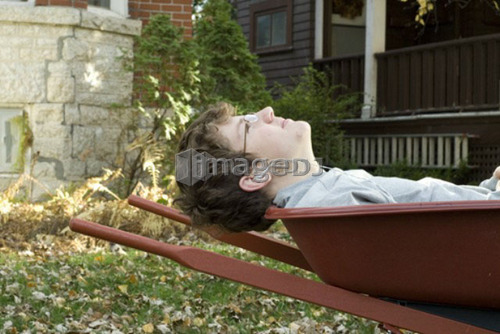 Teen boy listening to music in wheelbarrow, Winnipeg, Canada