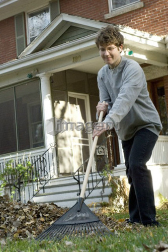 Teen boy listening to music while raking, Winnipeg, Canada